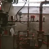 System rurka przeciwpożarowych z czerwonymi zaworami i manometrami. Widać tabliczkę "IN CASE OF FIRE".