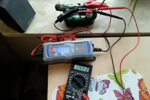 Ładowarka samochodowa Ultimate Speed pokazuje 14.3V, a multimetr Vorel 14.43V. Sprawdzamy, ile ładuje się akumulator.