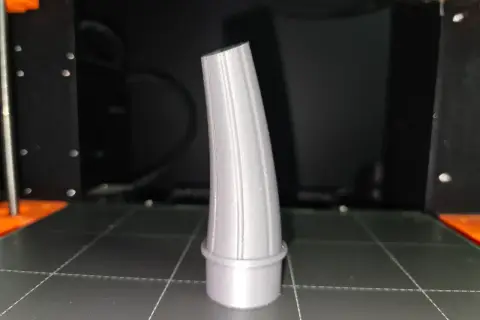 Szary lejek, wydrukowany na drukarce 3D, stoi na platformie roboczej.