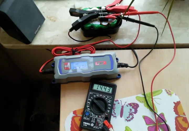 Ładowarka samochodowa Ultimate Speed pokazuje 14.3V, a multimetr Vorel 14.43V. Sprawdzamy, ile ładuje się akumulator.