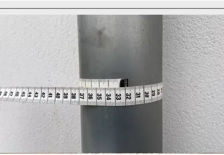 Miarka krawiecka owinięta wokół rury, pokazująca jej obwód. Odczyt wskazuje na średnicę około 32 cm.