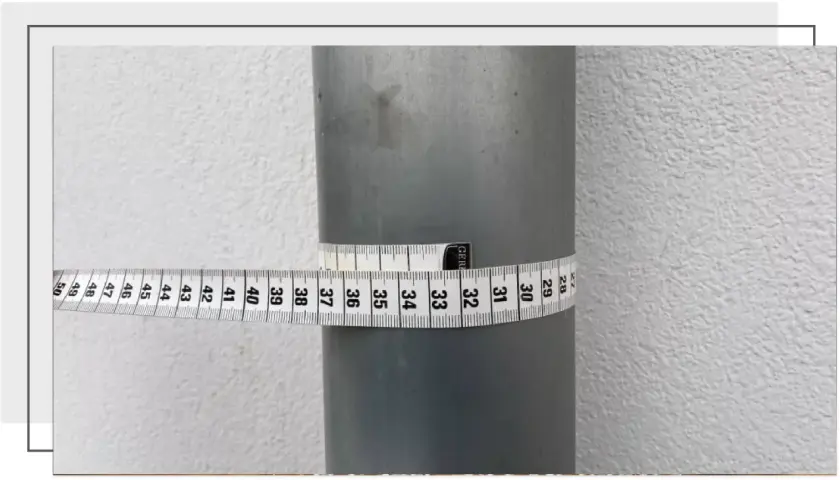 Miarka krawiecka owinięta wokół rury, pokazująca jej obwód. Odczyt wskazuje na średnicę około 32 cm.