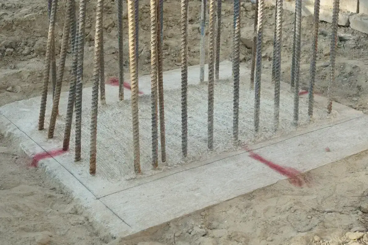 Zbrojenie wystające z betonowych stóp fundamentowych, gotowe do dalszych prac budowlanych.