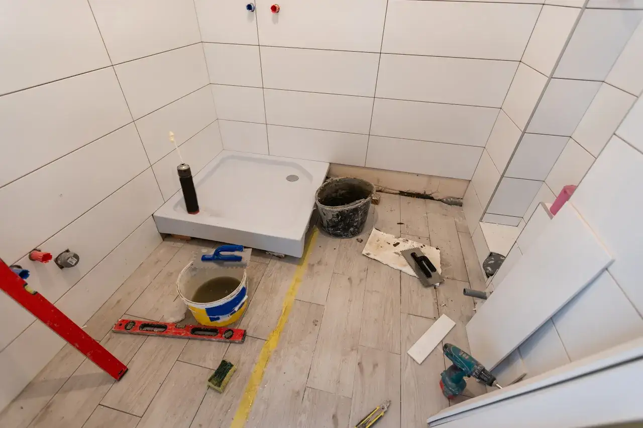 Remont łazienki 5m2: brodzik, wiadro z zaprawą, poziomica, kafelki i narzędzia. Koszt remontu łazienki 5m2 robocizna.
